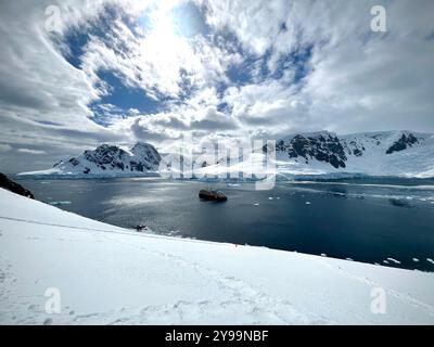 National Geographic Endurance anchored in a pristine bay at Graham Land, Antarctica, surrounded by dramatic snowy peaks and icy waters Stock Photo