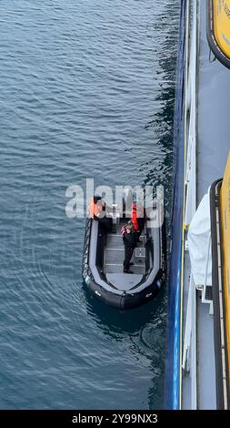 Crew members aboard a small expedition boat prepare for a landing in the waters of Antarctica, alongside the Lindblad Nat Geo Endurance Stock Photo