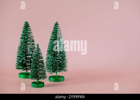Three small Christmas trees on pale pink background. Christmas, happy New Year greeting card Stock Photo