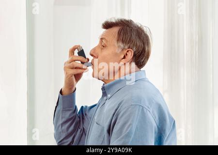 Physician examining mature man using blue asthma inhaler Stock Photo