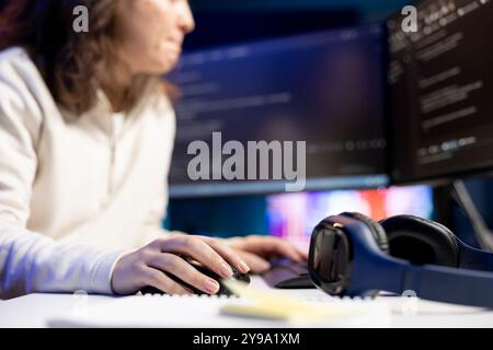 System administrator doing software debugging on PC at home, checking broken lines of code displayed on display. IT expert in living room fixing coding problems, typing on keyboard Stock Photo