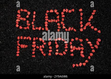 Black Friday words made with small red stones, on a background of black stones. Stock Photo