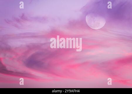A Full Moon Rises Among Violet Colored Clouds Set In Pastel Tones Stock Photo