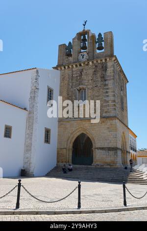 Historic church with bell tower, surrounded by white buildings, under a bright blue sky, Se Catedral de Faro, Cathedral of Faro, Largo da Se, Faro, Stock Photo