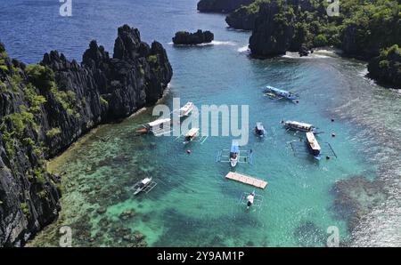 Aerial view of tropical island in Philippines. Boats in blue lagoons and lakes, white sand beach, rocks cliffs mountains and coral reef Stock Photo