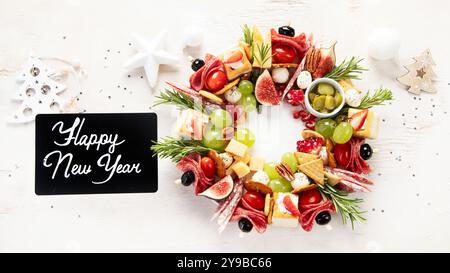 Christmas wreath of festive snacks. Cheese canapes with vegetables and salami on a white background. Christmas food wreath. Top view. Stock Photo