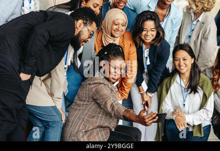 A smiling group of diverse professionals capture a joyful selfie during a lively and casual team gathering. Stock Photo