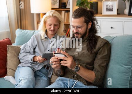 Young couple, boyfriend and girlfriend or husband and wife online shopping together from home on digital tablet. Happy man and woman using credit card Stock Photo
