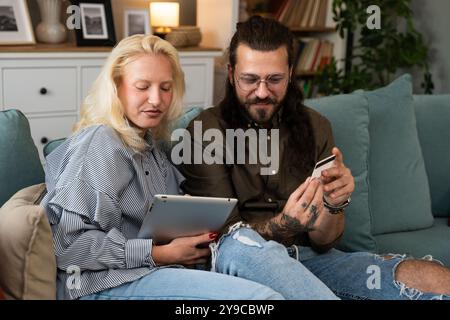 Young couple, boyfriend and girlfriend or husband and wife online shopping together from home on digital tablet. Happy man and woman using credit card Stock Photo
