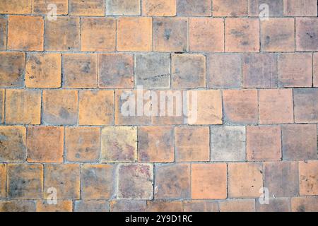 Orange brown white beige old shabby worn out floor tiles with damages cracks dirt caverns potholes and paint stains. Art retro grunge design Stock Photo