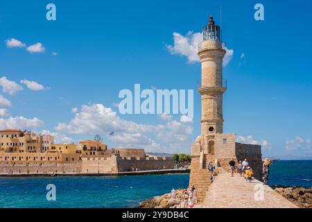 Harbour lighthouse Chania, view of people walking on the lighthouse seawall that encloses the historic inner harbour in Chania (Hania), Crete, Greece Stock Photo