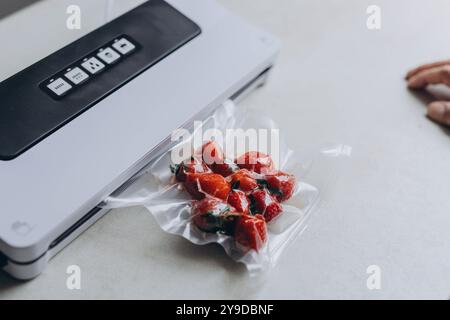 a man's hand is using a vacuum machine to vacuum pack strawberries into plastic bags. . High quality photo Stock Photo