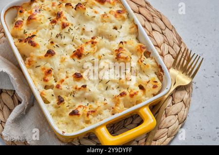 A cheesy macaroni and cheese cauliflower casserole in a yellow handled dish Stock Photo