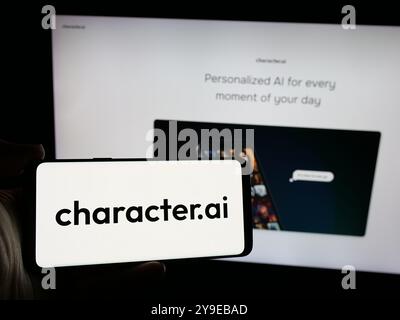 Person holding mobile phone with logo of Character Technologies Inc. (Character.ai) on screen in front of web page. Focus on phone display. Stock Photo