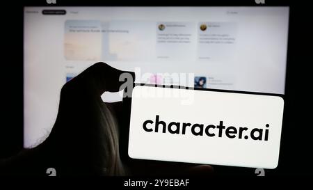 Person holding smartphone with logo of Character Technologies Inc. (Character.ai) on screen in front of website. Focus on phone display. Stock Photo