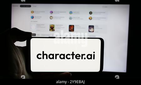 Person holding cellphone with logo of Character Technologies Inc. (Character.ai) on screen in front of business webpage. Focus on phone display. Stock Photo