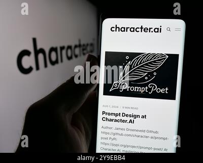 Person holding cellphone with webpage of Character Technologies Inc. (Character.ai) on screen in front of logo. Focus on center of phone display. Stock Photo