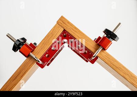 set of red anoodised aluminium woodworking cabinet corner clamps with fixing bolts and knobs to create a right angle Stock Photo