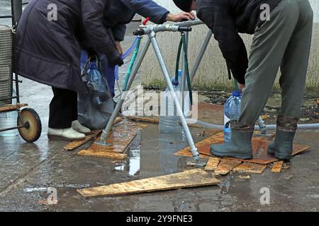 Residents of the city collect drinking water from a public tap Stock Photo