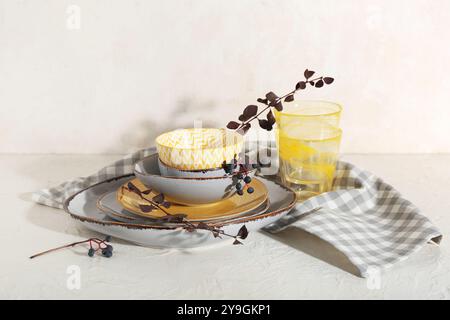Stack of dishes with autumn branches on table against white background Stock Photo