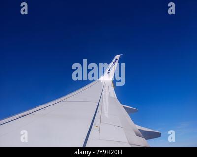 Wing of Ryanair passenger plane in the blue sky viewed from window Stock Photo