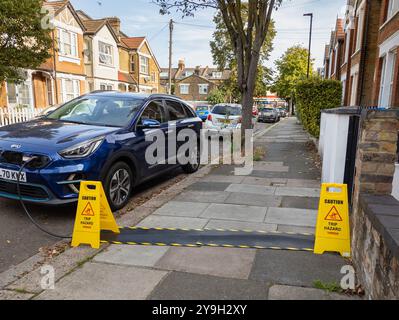 Kia electric car charging on a residential street from house using pavement cable protectors for the EV charging cable, London, UK Stock Photo
