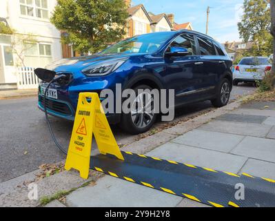 Kia electric car charging on a residential street from house using pavement cable protectors for the EV charging cable, London, UK Stock Photo