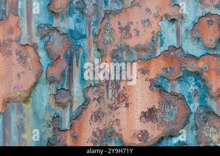 Rusting metal shows the effects of weathering and time, creating a textured surface with peeling paint and corrosion. Stock Photo