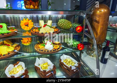 Cheese and fruit display with pineapples, apples and mango slices arranged on buffet counter hotel. Curacao. Stock Photo