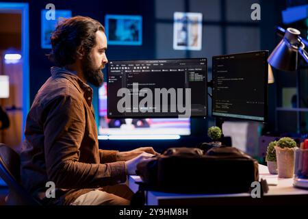 Developer in neon lit apartment implement security measures, protecting company systems and data. System administrator working from home, testing and debugging Javascript code Stock Photo