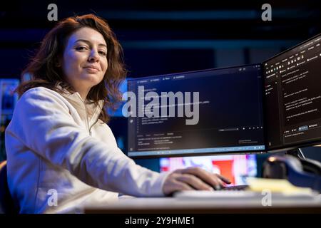 Portrait of smiling IT professional working from home developing software in Java programming language using desktop PC. Joyous developer in apartment writing lines of binary code on computer Stock Photo
