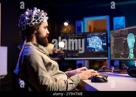 Software engineer specializing in AI using EEG headset to upload consciousness into computer. IT expert using high tech gear to create connection between brain and PC Stock Photo