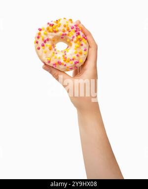 Female hand holding white chocolate donut with multicolor sprinkles over white background. Top view, flat lay. Sweet, dessert, diet concept. Banner wi Stock Photo