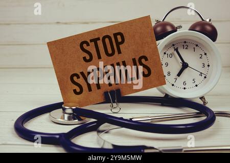 Stop Syphilis text message on paper card with stethoscope and alarm clock on wooden background Stock Photo