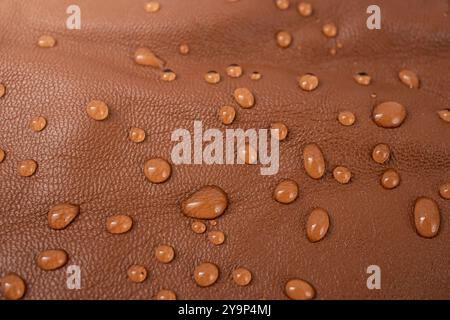 Water drops on red brown leather texture, top view, soft focus close up abstract Stock Photo