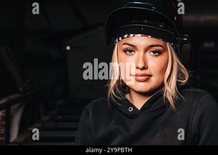 Woman in work gloves and welding helmet, holding a torch in a workshop Stock Photo