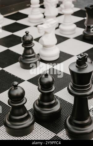 Giant black and white chess pieces on a checkered outdoor board Stock Photo