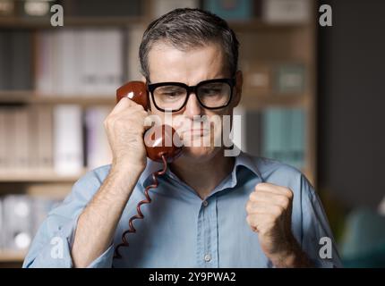 Angry stressed businessman having a phone call in the office Stock Photo