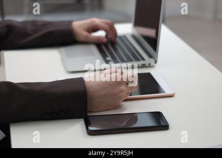 Businessman using different devices at white table indoors, closeup. Modern technology Stock Photo