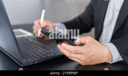 Businessman using mobile smart phone and online working on laptop computer, surfing the internet, searching the information at office. Female student Stock Photo