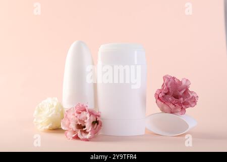 Different deodorants and beautiful eustoma flowers on beige background Stock Photo