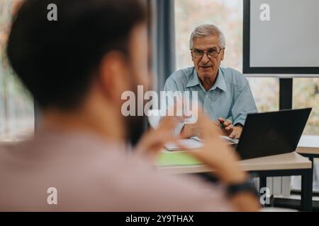 Elderly professor engaging with students in classroom discussion Stock Photo