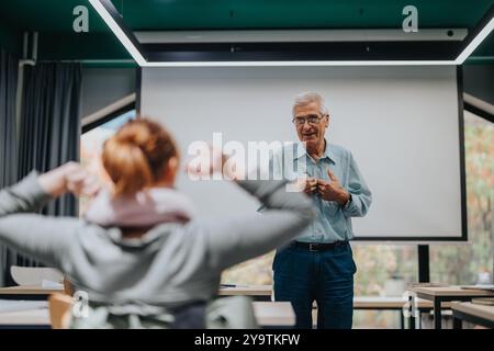Elderly professor engaging with students in a modern classroom Stock Photo