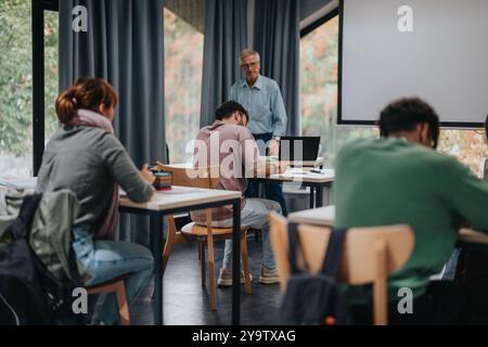 Students engaged in a classroom session with elderly professor Stock Photo