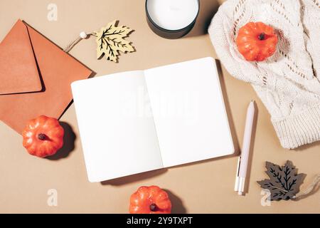 Autumn flat lay with open notepad, pumpkins, autumn leaves and candle on neutral background in sunlight. Top view, mockup. Stock Photo