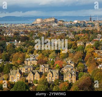 Blackford and the Grange areas of, Edinburgh, Scotland, UK. 11 October. Autumn colour is showing this year three weeks earlier than 2023, similar colours were photographed on November 5th last year. Temperature 11 degrees with a chilly SW wind at 26 km/h. Pictured: From Blackford Hill looking towards Edinburgh Castle under a broody sky and the Fife coast beyond, vibrant colour of the deciduous trees. Credit: Archwhite/alamy live news. Stock Photo