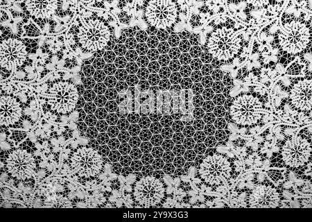 Beautiful white knitted lace on black background. Vintage embroidery pattern. Fabric texture. Stock Photo