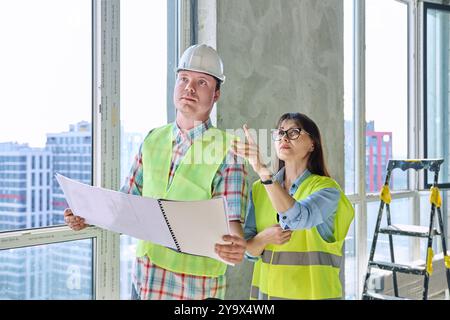 Colleagues in protective vest helmet working together on new construction site Stock Photo