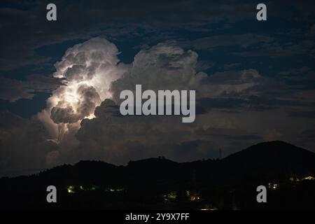 Nighttime thunderstorm clouds over the hilly Tuscan countryside, Italy, are illuminated by lightning from within. Tuscany, Italy. Stock Photo