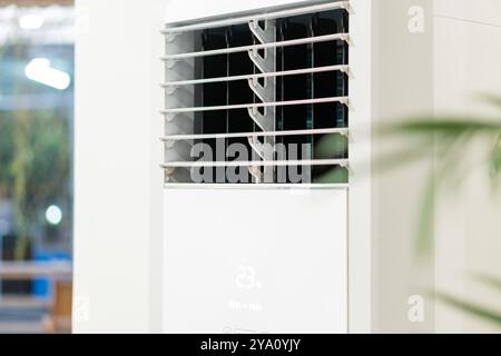 A close-up view of a modern air conditioning unit mounted on a wall. The unit features a sleek design with adjustable louvers and a digital display sh Stock Photo